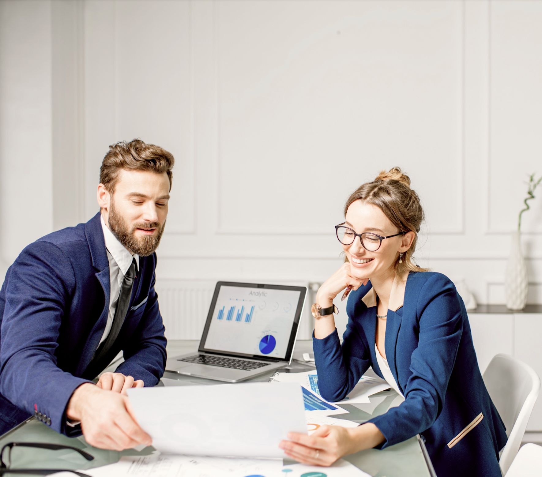 man and woman sitting at conference table looking at charts