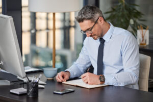 business man at desk writing notes